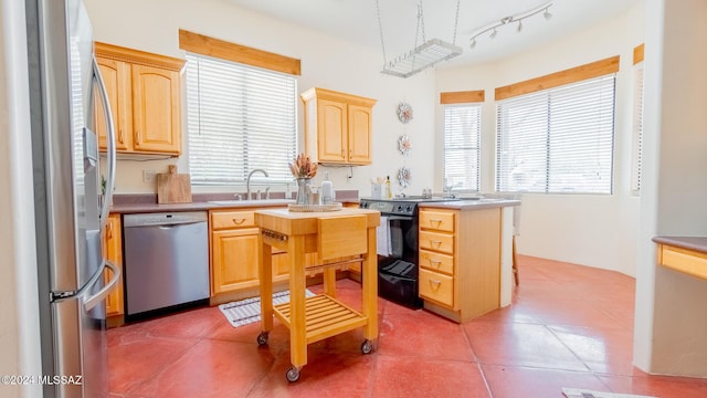 kitchen with appliances with stainless steel finishes, tile patterned floors, light brown cabinetry, and sink