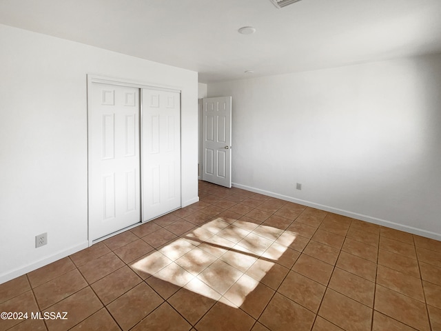 unfurnished bedroom featuring a closet and dark tile patterned flooring