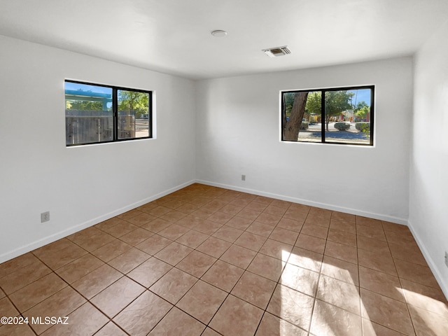 tiled spare room featuring a healthy amount of sunlight