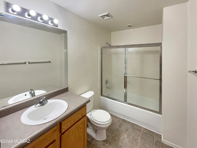 full bathroom featuring tile patterned floors, vanity, toilet, and enclosed tub / shower combo