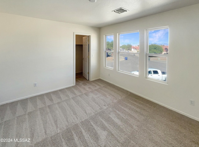 unfurnished bedroom featuring light colored carpet, a spacious closet, and a closet