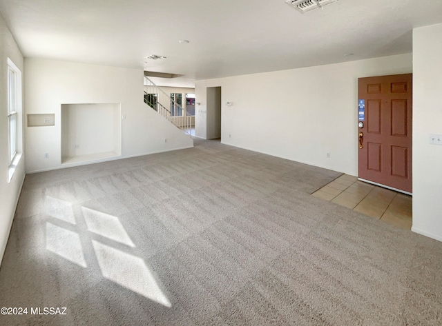 unfurnished living room featuring plenty of natural light and light colored carpet