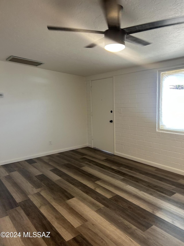 empty room with a textured ceiling, ceiling fan, and dark hardwood / wood-style floors