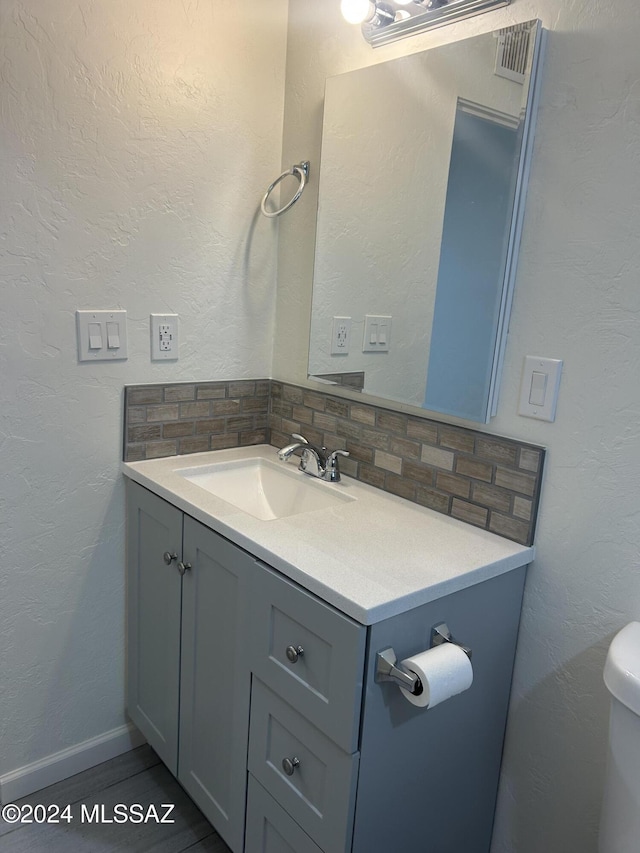 bathroom featuring vanity, backsplash, and toilet