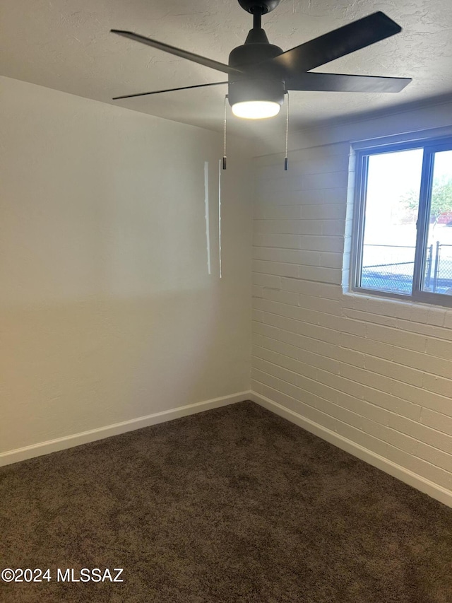 carpeted empty room featuring ceiling fan, brick wall, and a textured ceiling