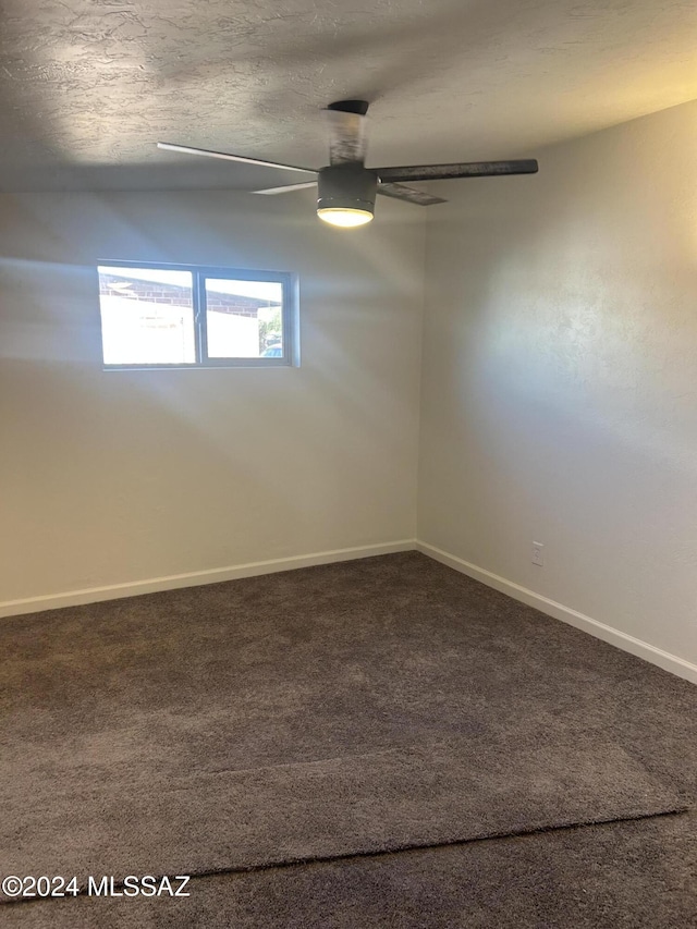 empty room featuring dark colored carpet, a textured ceiling, and ceiling fan