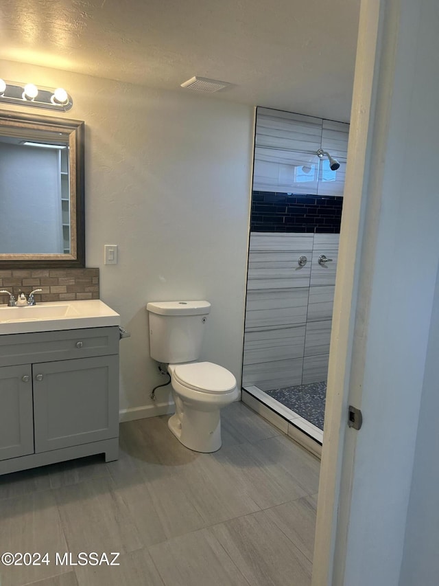 bathroom with a tile shower, vanity, and toilet