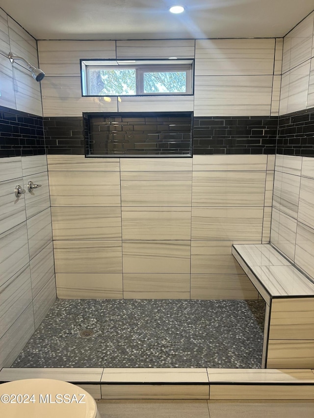 bathroom with a tile shower and toilet