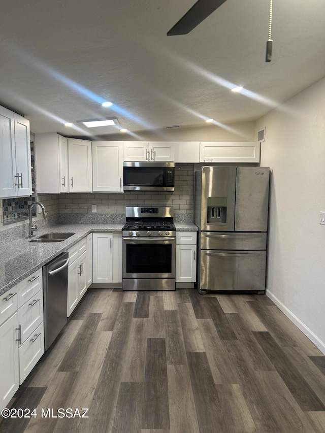 kitchen featuring appliances with stainless steel finishes, tasteful backsplash, light stone counters, sink, and white cabinetry