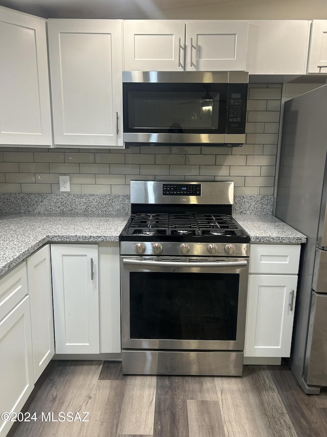 kitchen with white cabinets, appliances with stainless steel finishes, and dark hardwood / wood-style floors