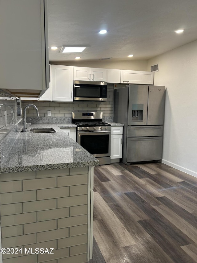 kitchen featuring light stone countertops, stainless steel appliances, sink, white cabinets, and dark hardwood / wood-style floors