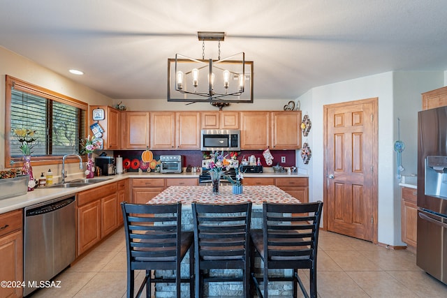 kitchen featuring sink, a notable chandelier, pendant lighting, light tile patterned flooring, and appliances with stainless steel finishes