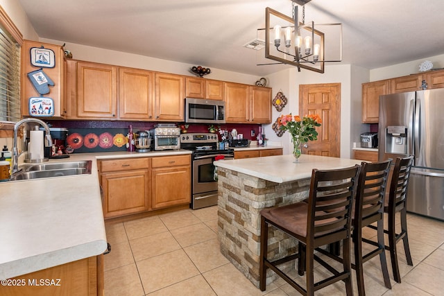 kitchen featuring appliances with stainless steel finishes, a sink, light countertops, light tile patterned floors, and a chandelier