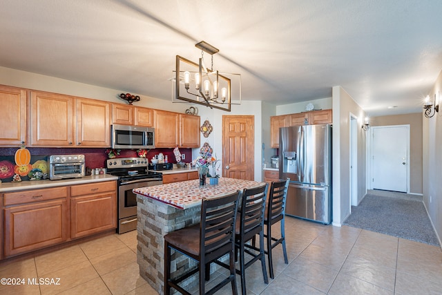 kitchen with a center island, hanging light fixtures, stainless steel appliances, a kitchen bar, and light tile patterned flooring