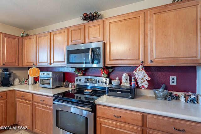 kitchen with appliances with stainless steel finishes, a textured ceiling, and light tile patterned floors