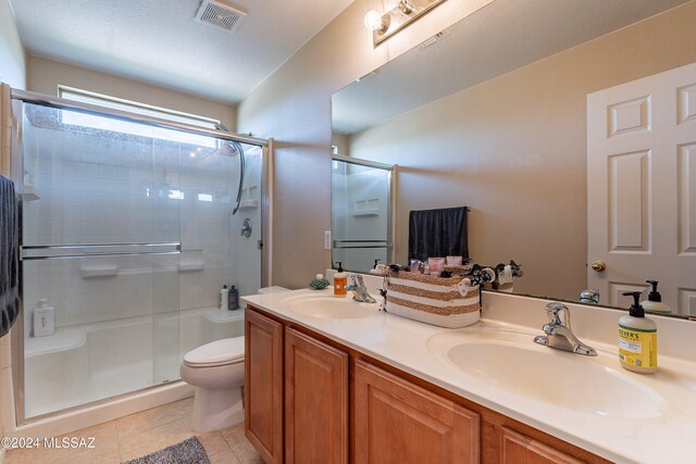 bathroom with toilet, vanity, tile patterned floors, and walk in shower