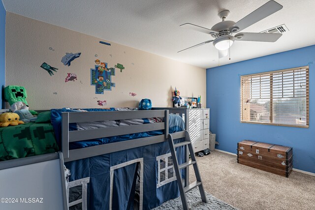 carpeted bedroom with ceiling fan and a textured ceiling