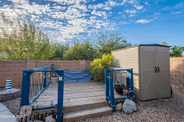 wooden terrace featuring a fenced backyard, a storage shed, and an outdoor structure