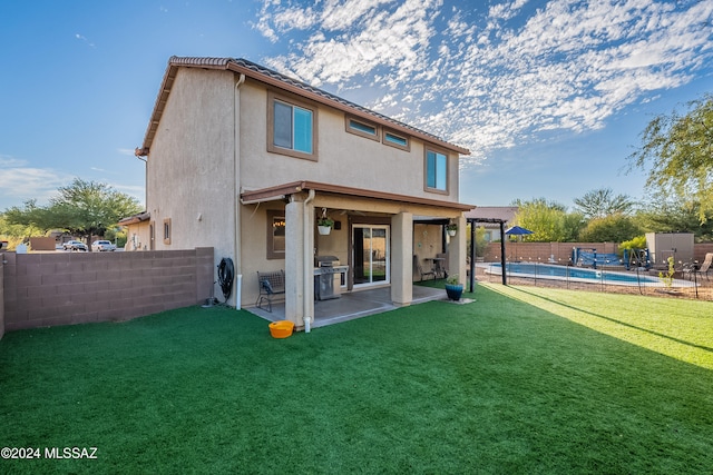 rear view of house featuring a patio area, a yard, and a fenced in pool