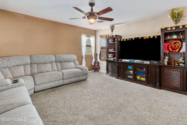 carpeted living area with ceiling fan and baseboards
