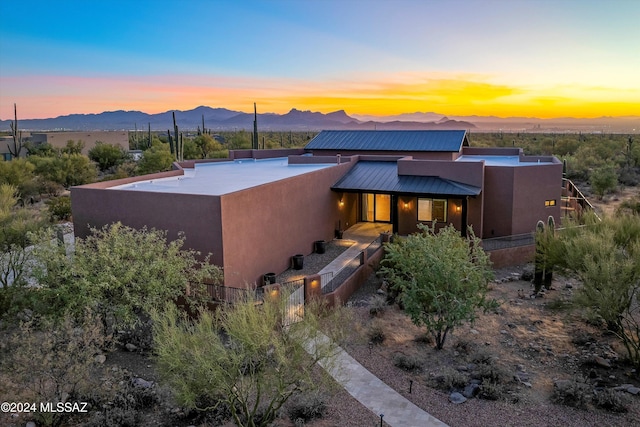 view of front facade with metal roof, a mountain view, and stucco siding