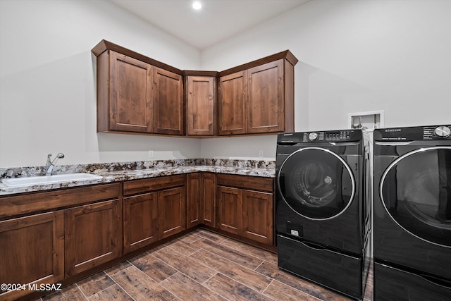 laundry area featuring a sink, cabinet space, wood finish floors, and washing machine and clothes dryer
