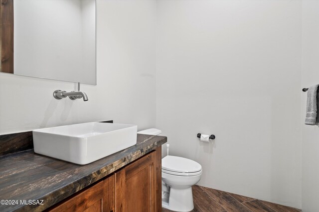 half bathroom with vanity, toilet, and wood finished floors