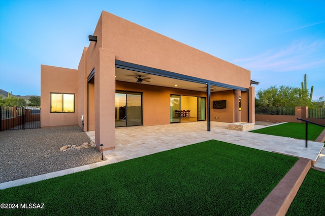 rear view of property featuring stucco siding, a patio, a yard, and fence