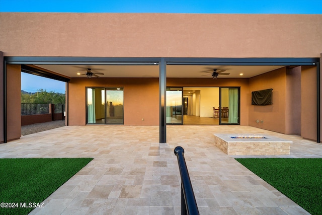 rear view of property featuring stucco siding, a patio, an outdoor fire pit, and ceiling fan