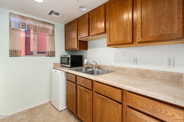 kitchen featuring dishwasher, sink, and light tile patterned floors