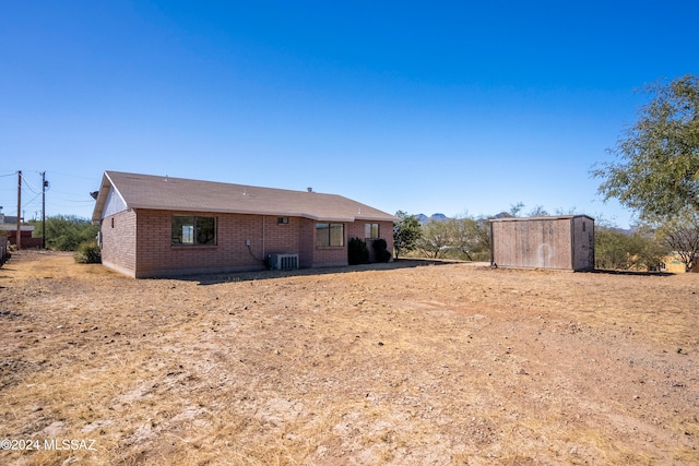 rear view of property with central AC unit and a storage unit