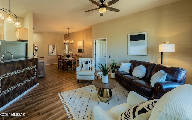 living room with ceiling fan with notable chandelier and dark wood-type flooring