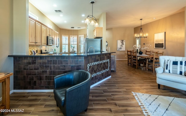 kitchen with pendant lighting, light brown cabinets, dark wood-type flooring, a notable chandelier, and stainless steel appliances