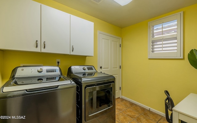 laundry area featuring washer and clothes dryer, light tile patterned floors, and cabinets