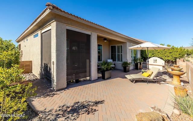 rear view of property featuring ceiling fan and a patio area