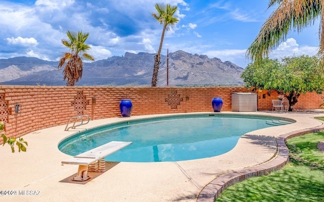 view of pool with a mountain view, a patio, and a diving board