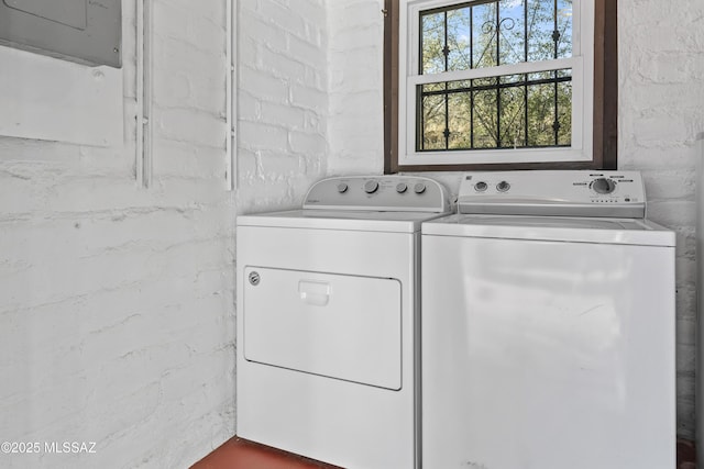 washroom featuring independent washer and dryer, electric panel, and brick wall