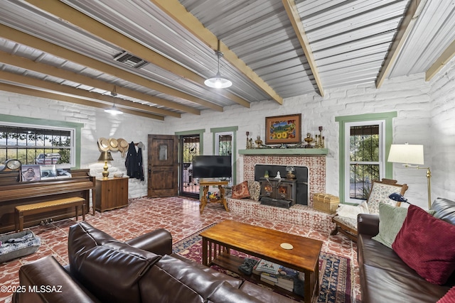 living room featuring beam ceiling and a wood stove