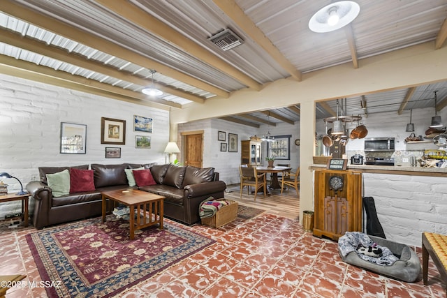 living room featuring beamed ceiling and brick wall