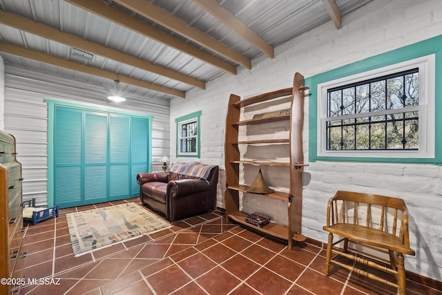 living area with beamed ceiling and brick wall