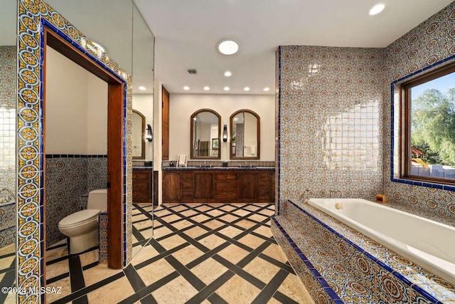 bathroom featuring a bathing tub, vanity, tile walls, and toilet