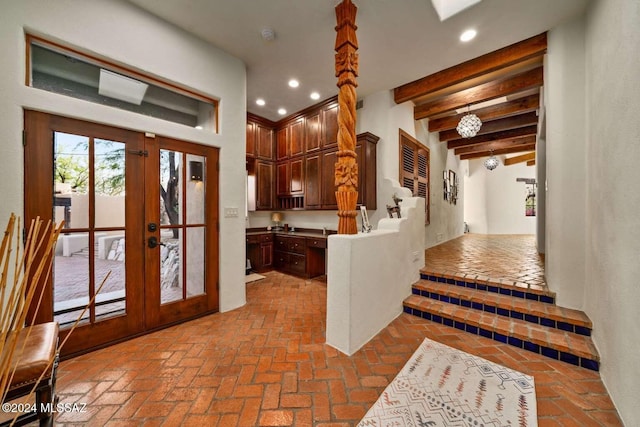 kitchen featuring kitchen peninsula, beam ceiling, and french doors