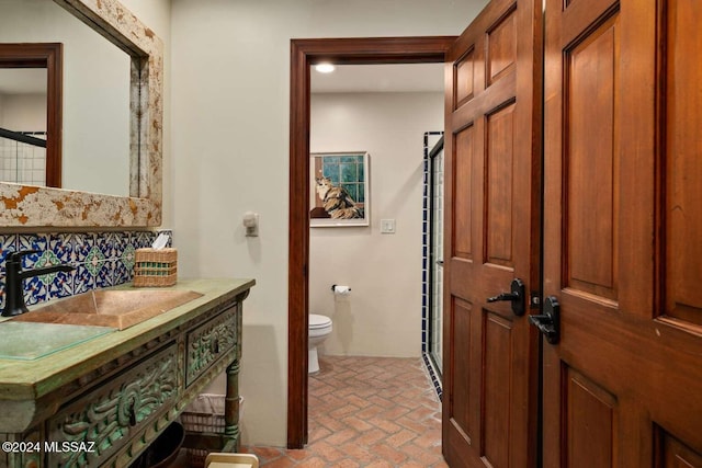 bathroom with decorative backsplash, toilet, and vanity