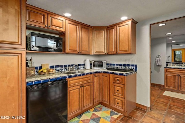 kitchen featuring sink, tile countertops, dark tile patterned flooring, and black appliances