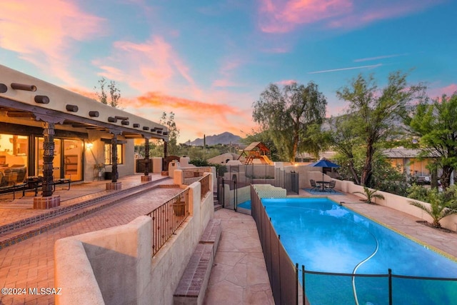 pool at dusk with a mountain view and a patio