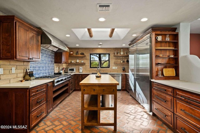 kitchen featuring a center island, backsplash, ventilation hood, a skylight, and stainless steel appliances