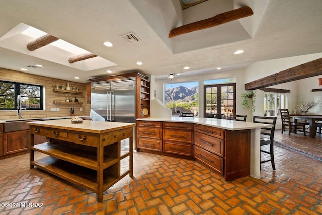 kitchen featuring decorative backsplash, french doors, sink, a center island, and built in refrigerator