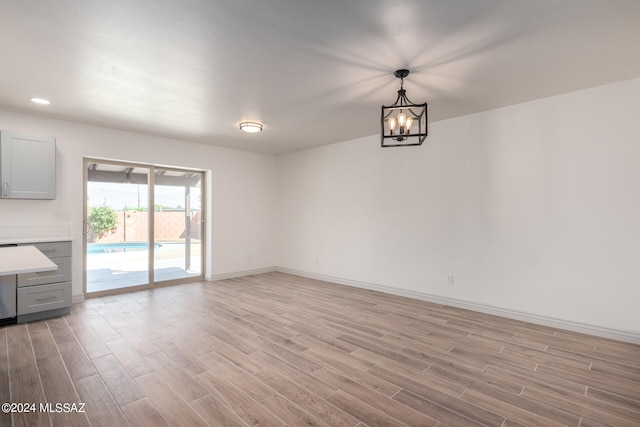 unfurnished living room with a notable chandelier and light hardwood / wood-style floors