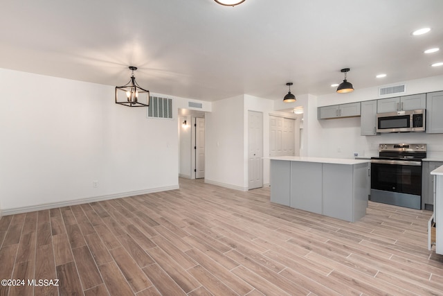 kitchen featuring appliances with stainless steel finishes, light hardwood / wood-style flooring, a center island, gray cabinets, and hanging light fixtures