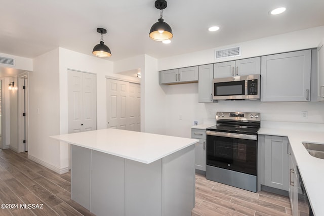 kitchen with pendant lighting, gray cabinetry, appliances with stainless steel finishes, and light hardwood / wood-style flooring